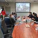 group of people sitting at a table in a meeting room looking at presentation on screen