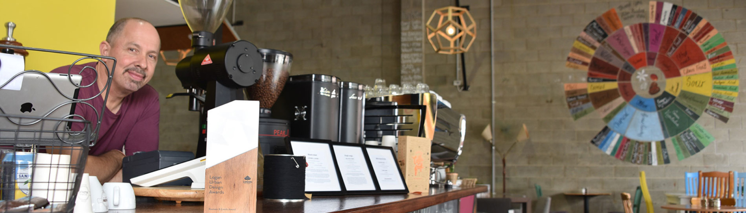 Smiling man standing at a bench behind a coffee grinder