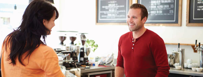 Man and woman smiling at each other in a cafe