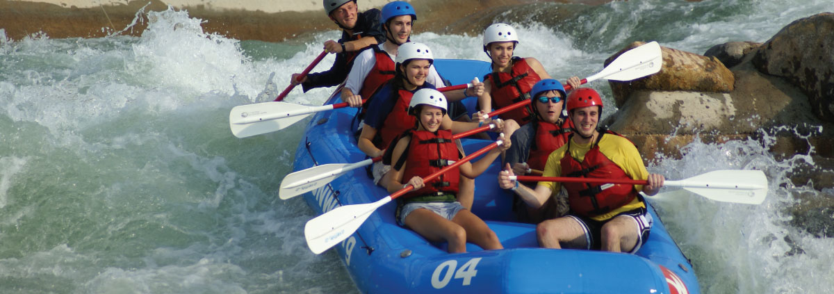 Seven people in whitewater raft paddling down rapids