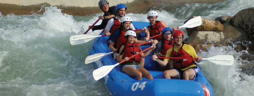 Seven people in whitewater raft paddling down rapids
