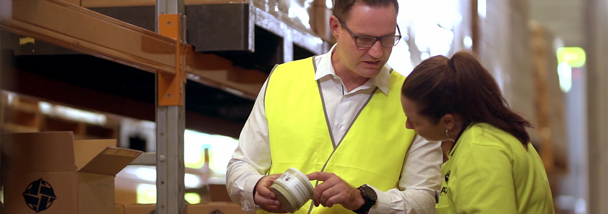 Man checking packaging with female in warehouse