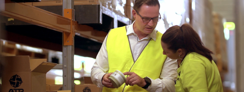 Man checking packaging with female in warehouse