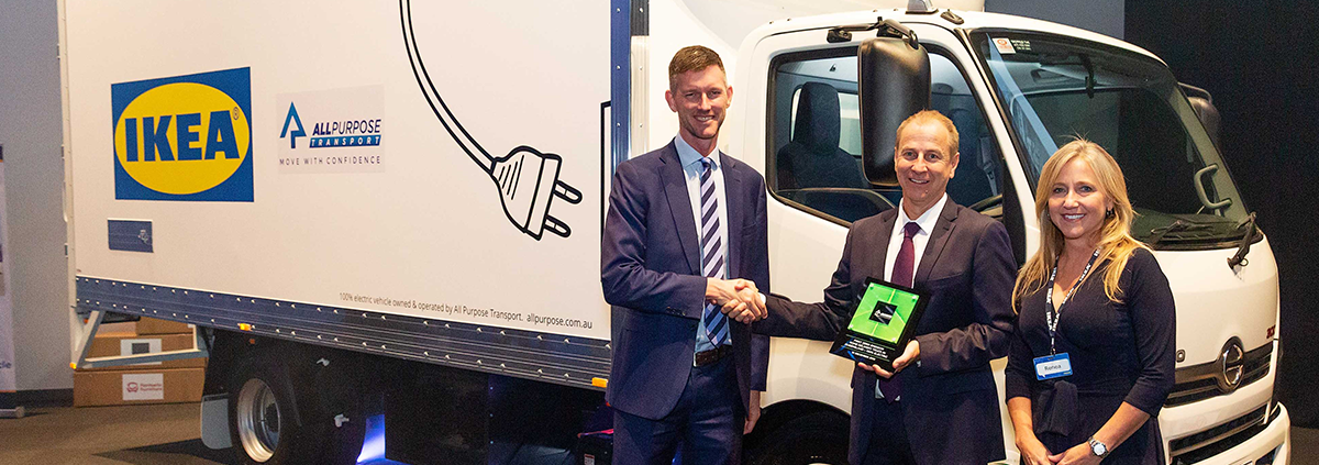 Woman smiling and two men shaking hands in front of a IKEA truck