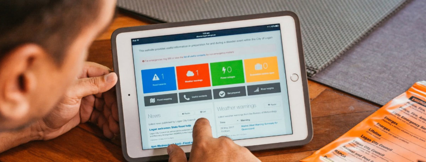 Man using tablet computer, with Logan Disaster Dashboard on the screen