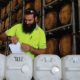 Man putting labels on sanitiser bottles in rum barrel warehouse