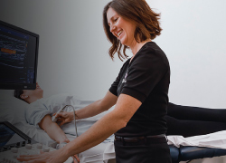 Woman using ultrasound on man's arm