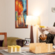 Woman at dining table holding product - a home-based business