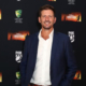Michael Kasprowicz standing in front of a media wall
