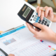 Image_an accountant using a calculator and showing charts and figure to a colleague.