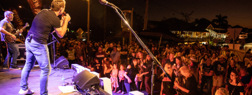 Man singing on stage to crowd at Jimboomba