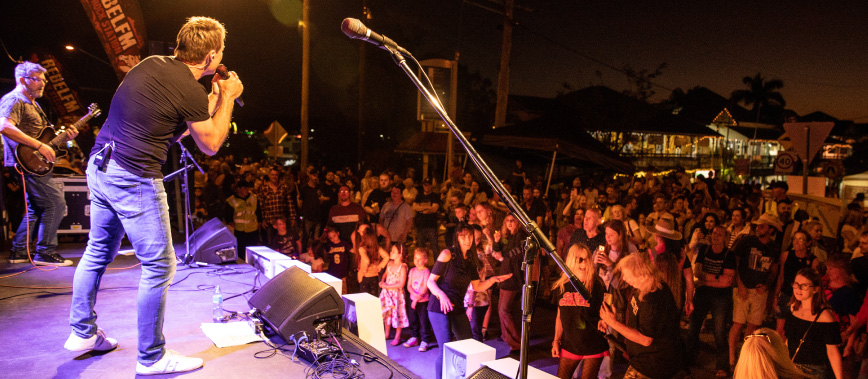 Man singing on stage to crowd at Jimboomba