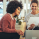 one lady looking at a report smiling and another lady looking at the laptop