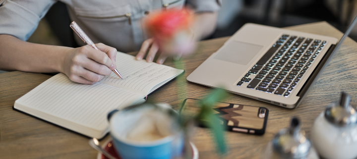 A woman witting on the notebook with her laptop, tea on the desk