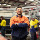 A tradesman standing in front of the machines crossing his arms and smiling at the camera