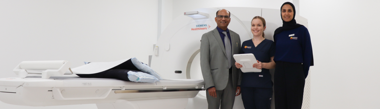 A doctor and two technicians standing in front of an MRI machine.