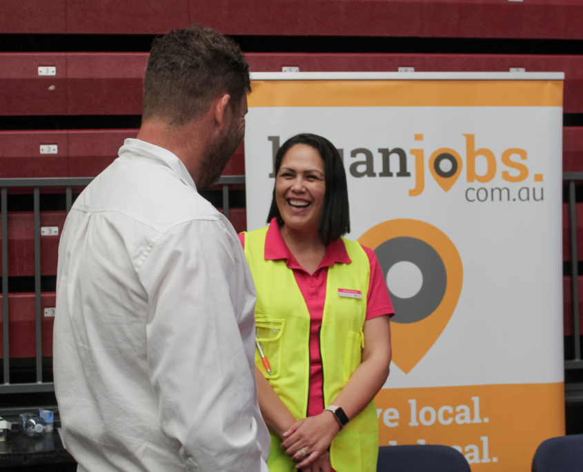 A staff standing in front of Logan Jobs banner talking to a job seeker